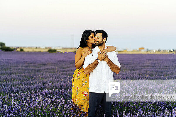 Junge Frau umarmt Mann im Lavendelfeld unter Himmel