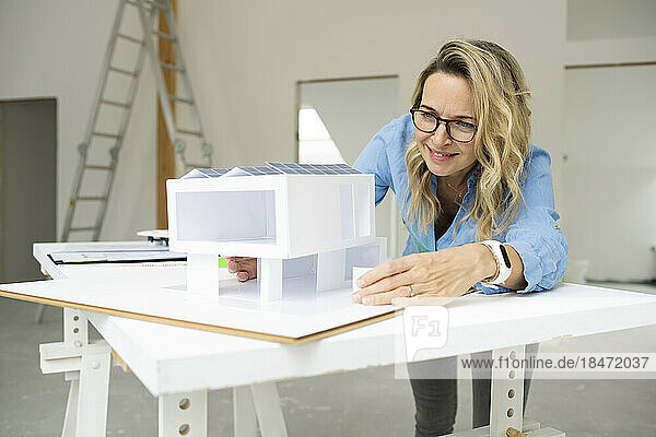 Smiling architect examining model home at site