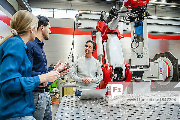 Business colleagues planning strategy in meeting at robot factory