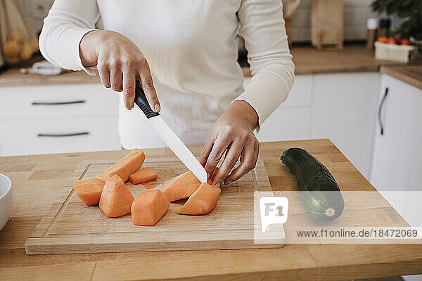 Hands of woman cutting vegetables in kitchen at home