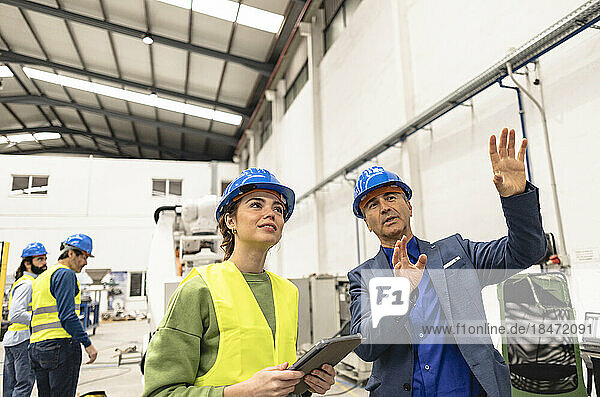 Smiling engineer explaining colleague in factory