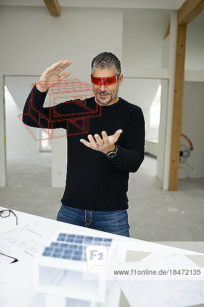 Architect wearing virtual reality simulator examining model home at construction site