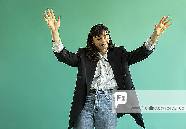 Young woman gesturing against green background