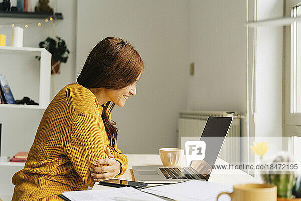 Happy female freelancer talking on video call through laptop