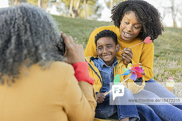 Woman talking photos of daughter and grandson sitting in park