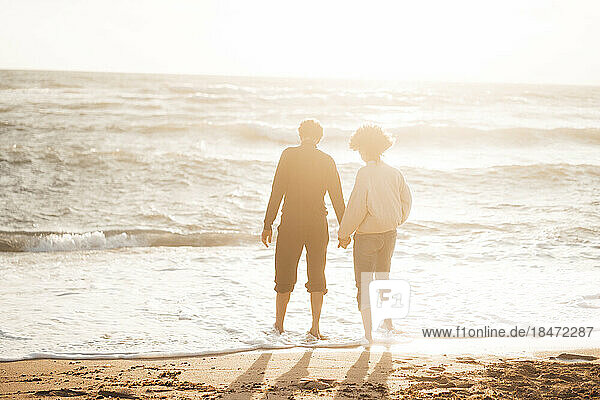 Man holding hands with woman standing at beach