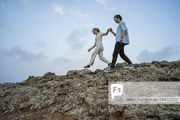 Junges Paar geht miteinander auf einem felsigen Berg spazieren