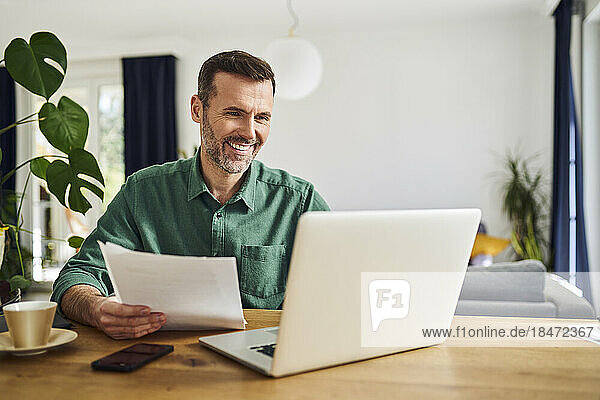 Confident businessman doing paperwork sitting at table working from home