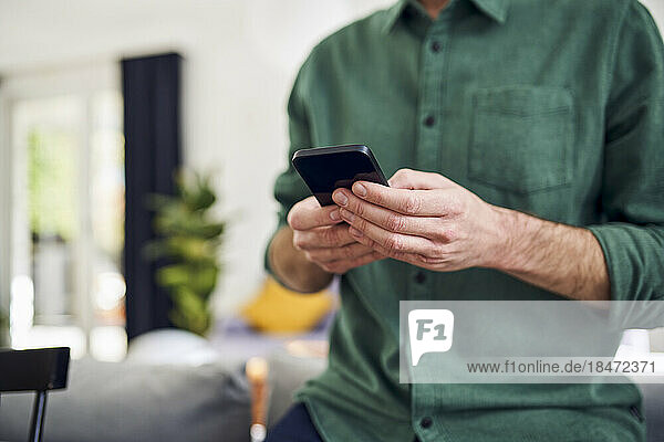Man using smartphone leaning on couch
