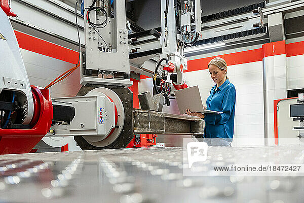 Mature engineer using laptop in modern robot factory