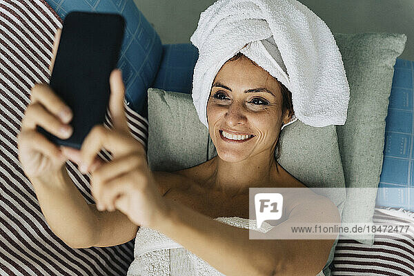 Happy woman taking selfie through smart phone at home
