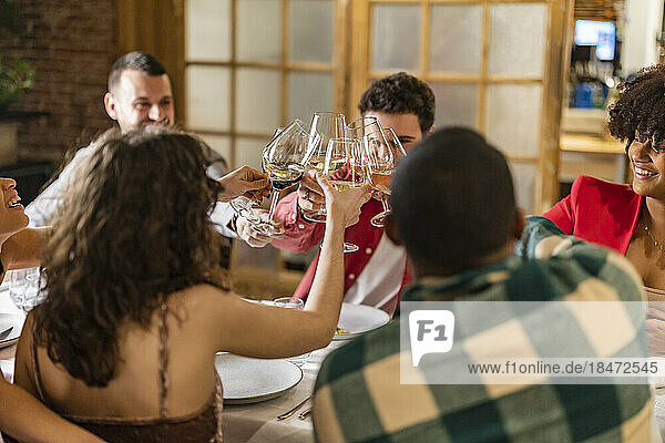 Happy friends toasting wineglasses having fun at restaurant