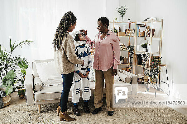 Family talking to girl wearing space suit standing in living room at home