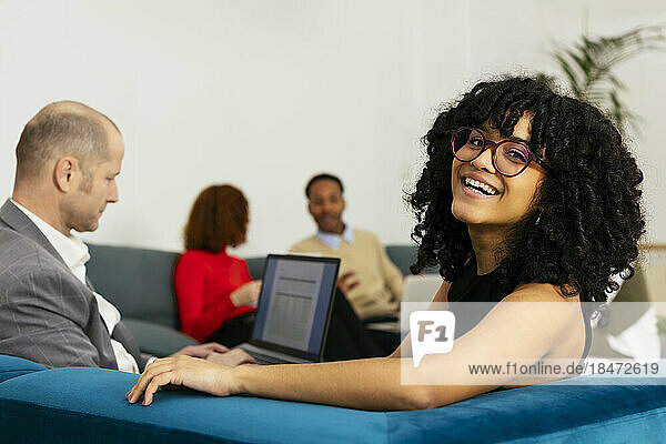 Young businesswoman with Afro hairstyle sitting with colleague in office