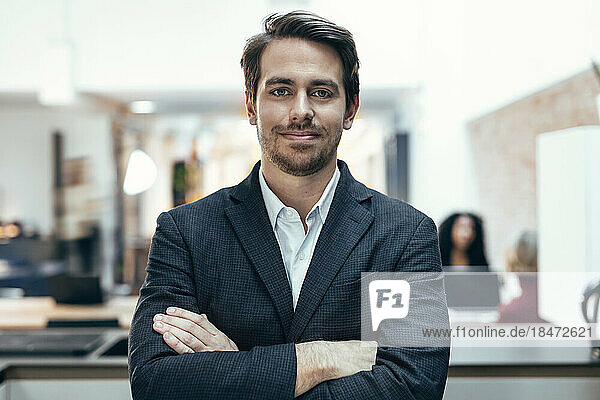 Smiling businessman with arms crossed standing at office