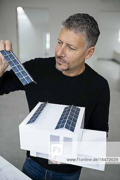 Mature architect examining solar panels of model home
