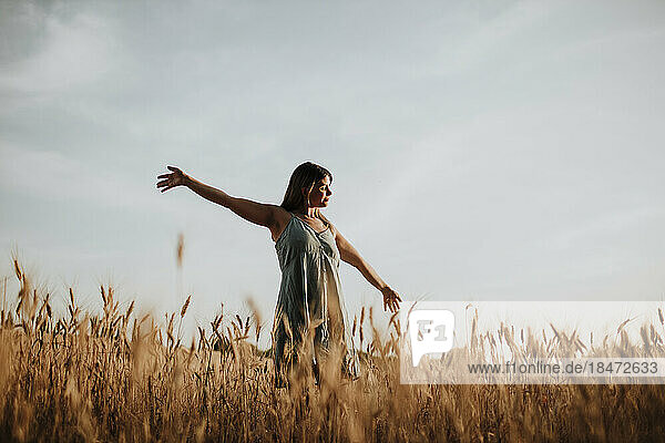 Young woman standing with arms outstretched in field