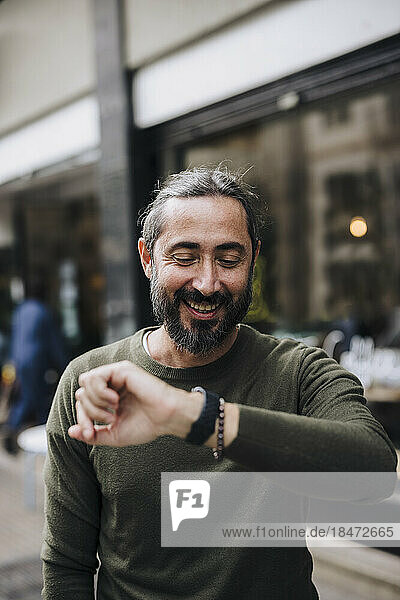 Happy mature man checking time on smart watch