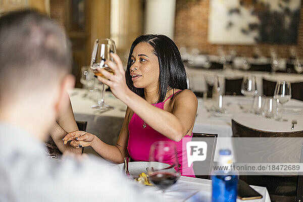 Young woman toasting wineglass with friends at restaurant