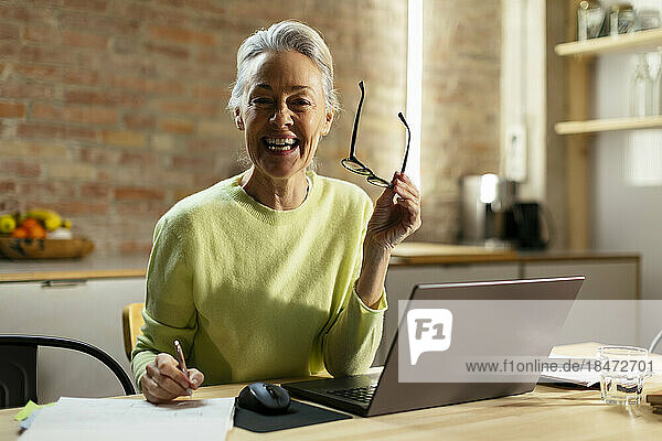 Happy freelancer with eyeglasses sitting at desk