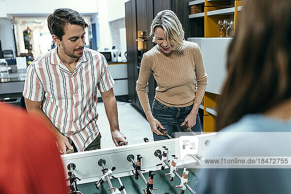 Happy colleagues playing foosball together at office