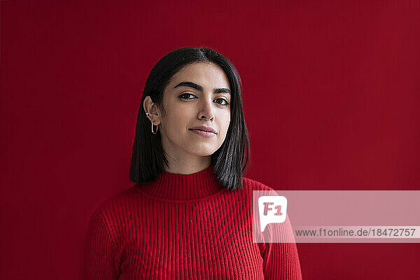 Confident young woman against red background