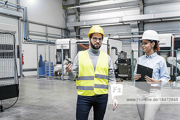 Smiling engineer talking with colleague in factory