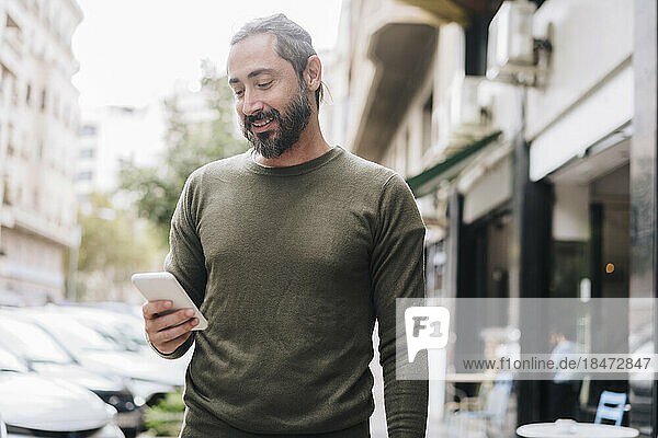 Smiling bearded man using smart phone