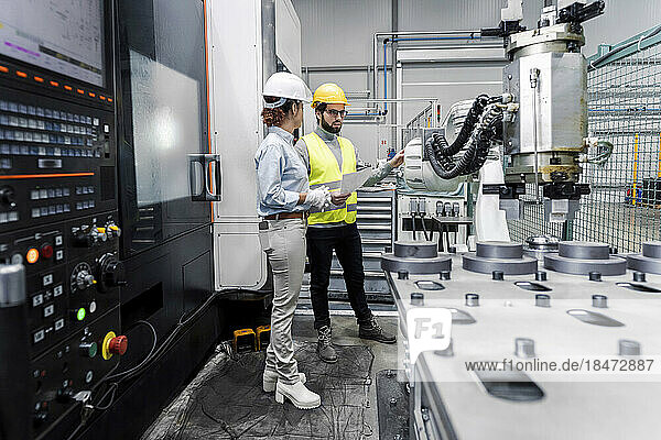 Young engineer and colleague having discussion in factory