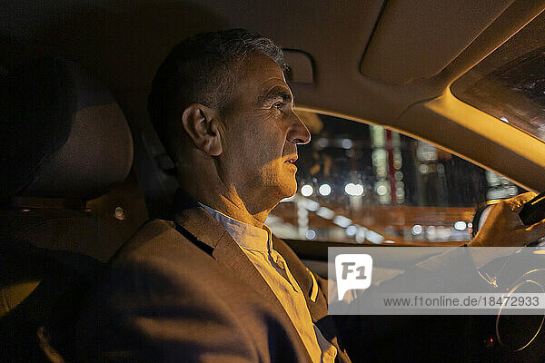 Businessman driving car at night