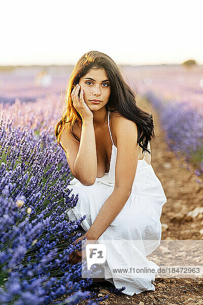 Beautiful woman crouching by lavender plants in field