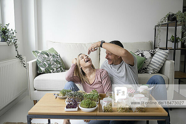 Happy couple eating homegrown herbs at home