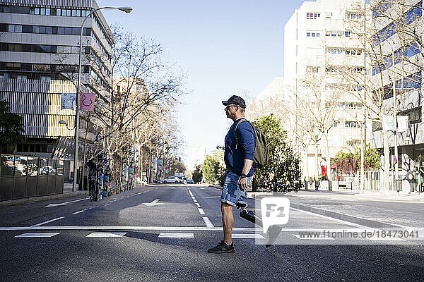 Mature man with prosthetic leg crossing road in city