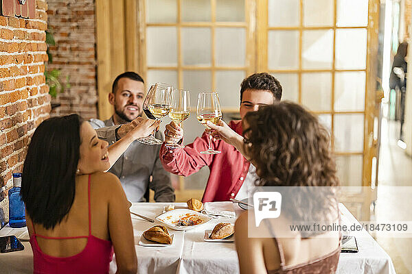 Young friends toasting wineglasses at restaurant