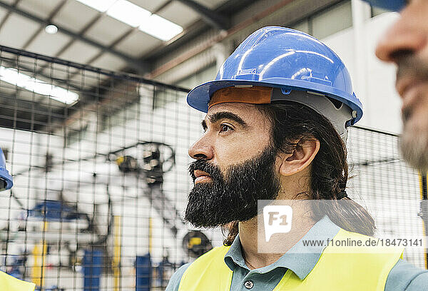 Thoughtful engineer with beard in factory