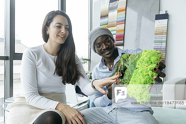 Smiling architects examining green wall sample in office