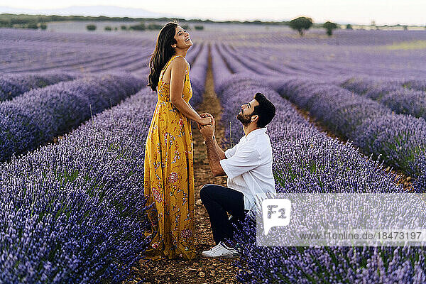 Man proposing woman standing in lavender field