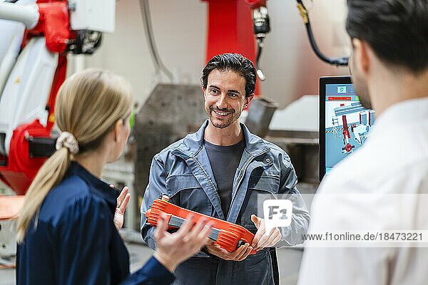 Lächelnder Ingenieur diskutiert mit Kollegen in der Fabrik