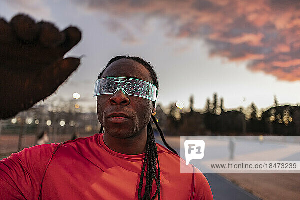 Young athlete wearing illuminated smart glasses at sunset