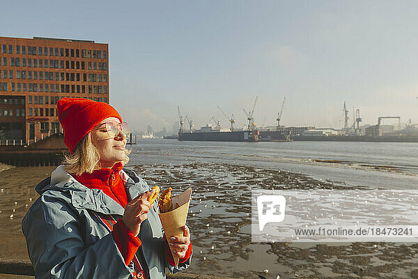Woman with eyes closed holding fish and chips