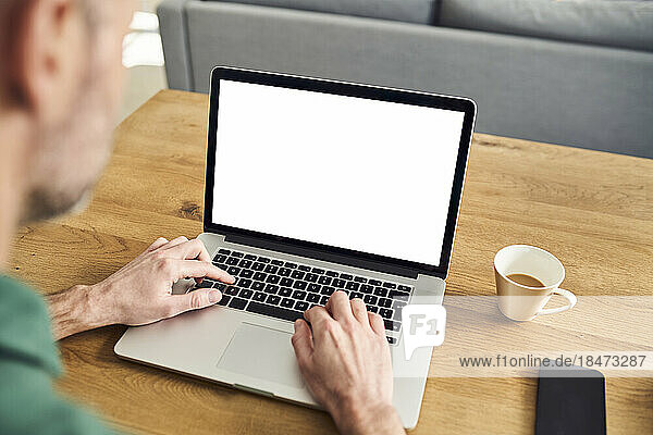 Man working on laptop with blank sctreen