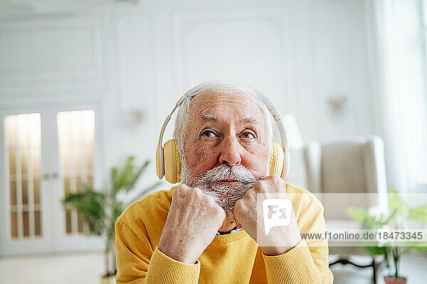 Senior man wearing wireless headphones at home