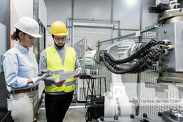 Ingenieur und Kollege diskutieren über Maschinenteil in der Fabrik