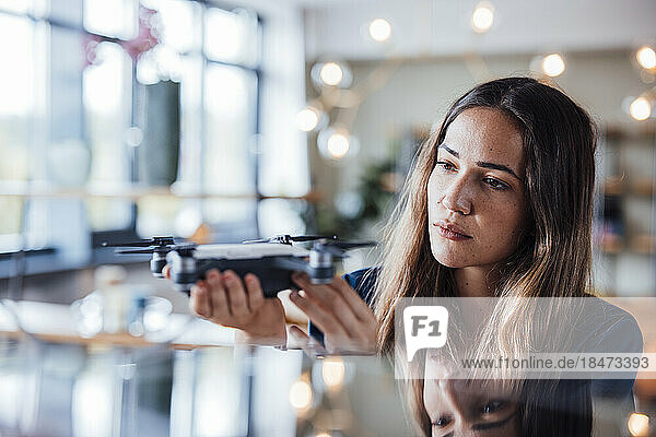 Young businesswoman examining drone in office