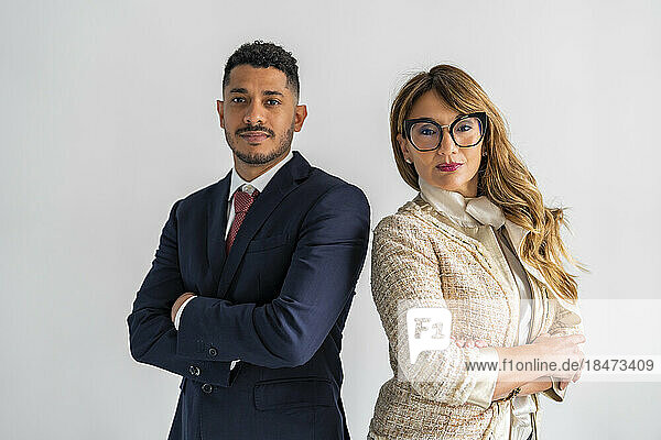 Confident mature businesswoman standing with colleague against white background