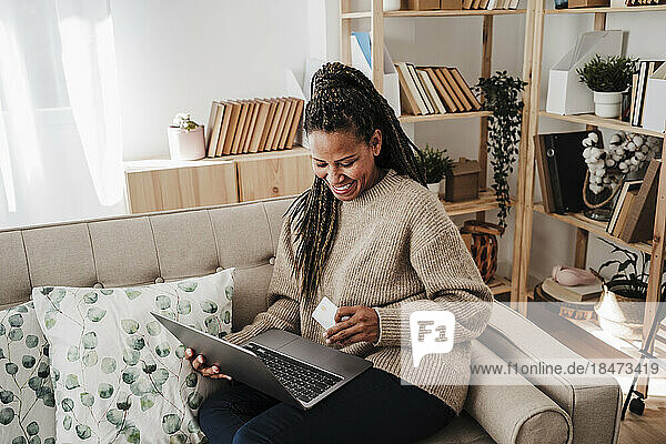 Happy woman doing online shopping through laptop and credit card at home