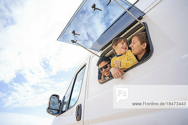 Happy parents with son looking through window of motor home