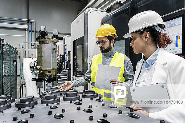 Ingenieur und Kollege untersuchen Maschinenteile in der Fabrik
