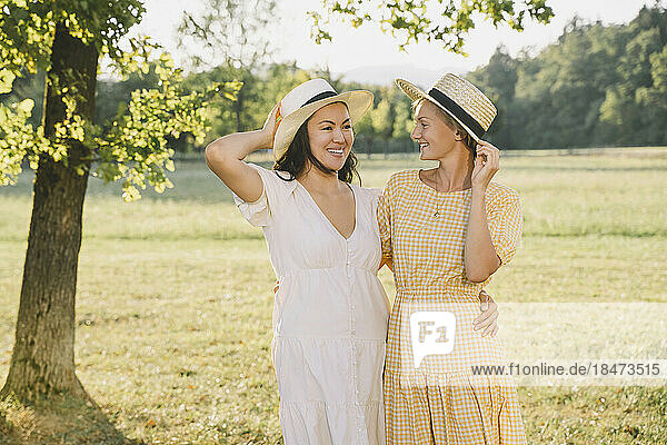 Happy women wearing hats standing in park