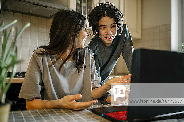 Happy boy teaching laptop to mother at home